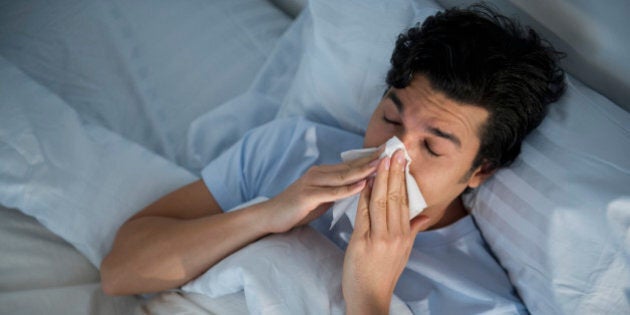 USA, New Jersey, Jersey City, man lying in bed and blowing nose