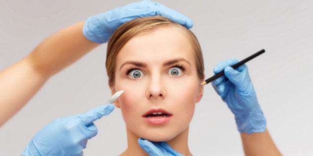 healthcare, beauty and medicine concept - beautiful woman face and beautician hands with pencil and scalpel