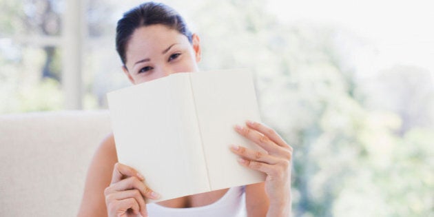 Woman holding book over mouth