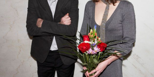 Couple with arms crossed man and woman holding flowers