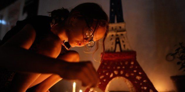 MANILA, PHILIPPINES - NOVEMBER 16: A young girl lights candles to honour victims of the Paris terror attacks at Alliance Francais Manila on November 16, 2015 in Manila, Philippines. 129 people were killed and hundreds more injured in Paris following a series of terrorist acts in the French capital on Friday night. (Photo by Dondi Tawatao/Getty Images)