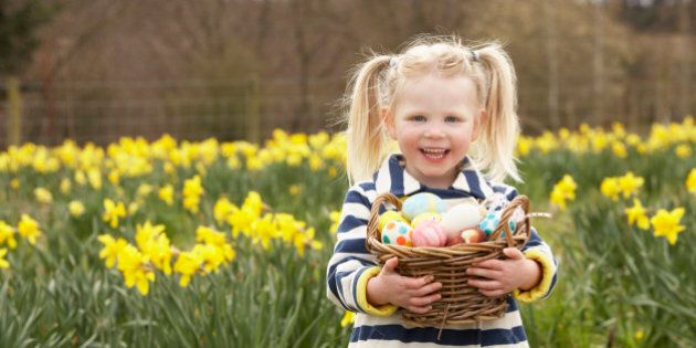 Young Girl Holding Basket Of Decorated Eggs In Daffodil Field