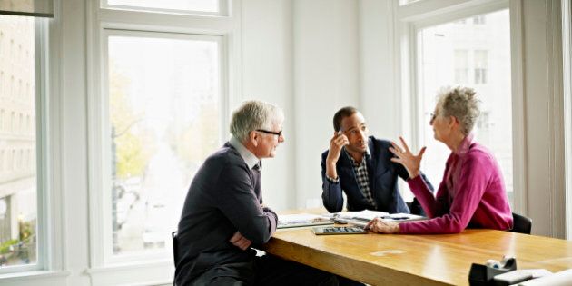 Group of three coworkers in discussion in conference room