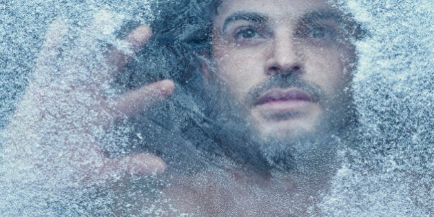 Hispanic man behind snow covered window