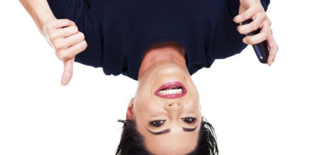 upside down view of young woman holding smart phone and giving thumb up
