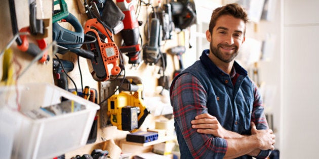 Portrait of a handsome young handyman standing in front of his work tools