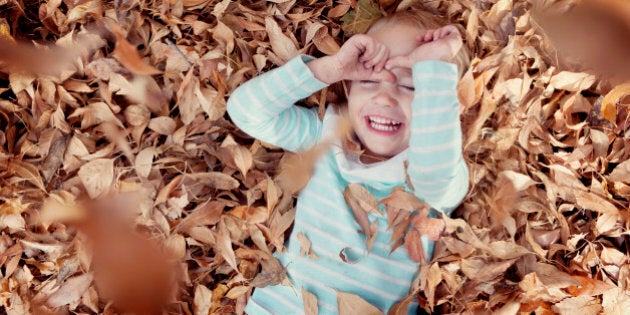 Little girl playing in fall leaves