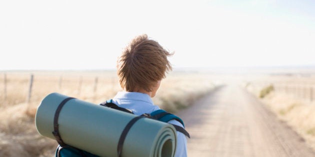 Man backpacking along country road