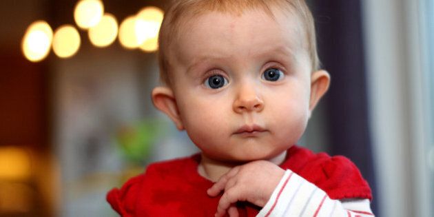 Cute baby with big blue eyes looking straight to camera.