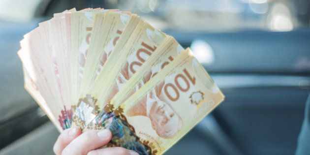 A woman counts $100 Canadian notes/bills before making a large purchase.