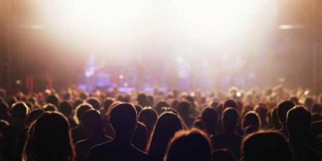 Crowd cheering and watching a band on stage.