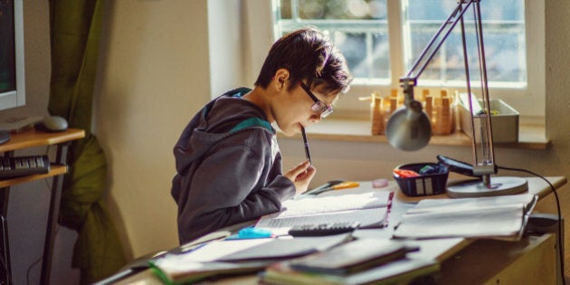 Boy doing his homework at desk in his room