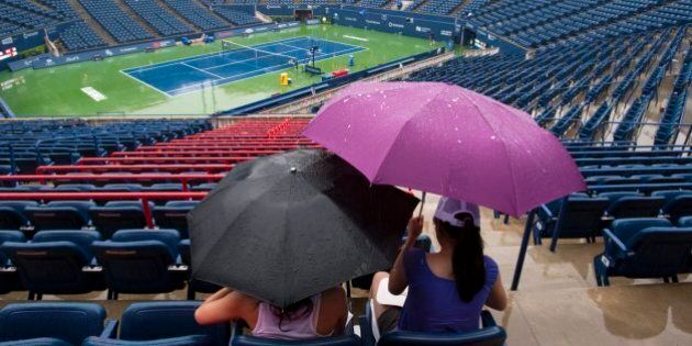 Fans shelter under umbrellas during a weather delay in Rogers Cup ATP tennis action in Toronto on Monday August 9, 2010. THE CANADIAN PRESS/Frank Gunn