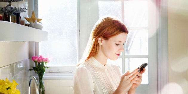 woman texting on mobile in kitchen