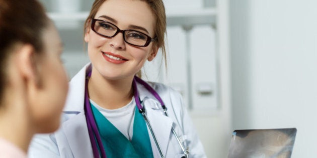 Smiling medicine female doctor in glasses explains to patient diagnosis pointing with pen to x-ray picture. Patient listening carefully doctors recommendations. Medical concept. Radiologist or traumatologist