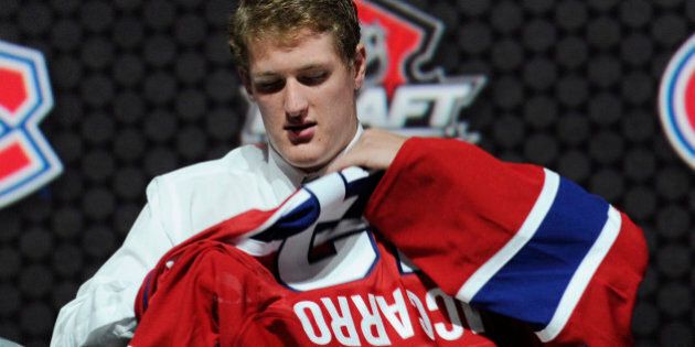 Michael McCarron, a winger, pulls on a Montreal Canadiens sweater after being chosen 25th overall in the first round of the NHL hockey draft, Sunday, June 30, 2013, in Newark, N.J. (AP Photo/Bill Kostroun)
