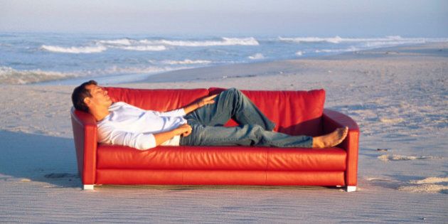 Man lying on sofa at beach