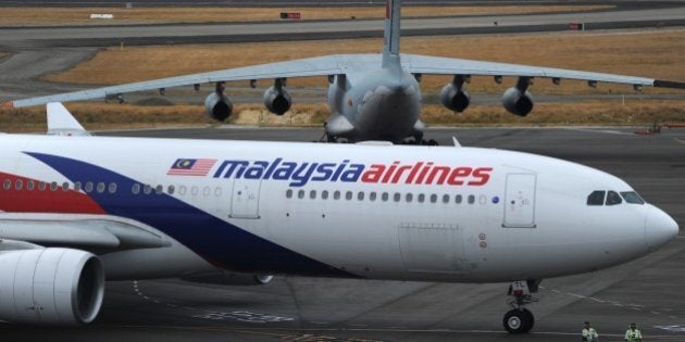 A Malaysia Airlines plane (below) prepares to go onto the runway and pass by a stationary Chinese Ilyushin 76 aircraft (top) at Perth International Airport on March 25, 2014. Wild weather halted the search on March 25 for wreckage from the Malaysia Airlines jet that crashed into the Indian Ocean, frustrating attempts to determine why it veered off course and bring closure to grieving relatives. AFP PHOTO / POOL / Greg WOOD (Photo credit should read GREG WOOD/AFP/Getty Images)