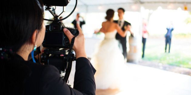 A wedding photographer captures the couple's first dance.