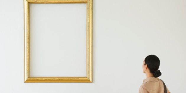 Woman looking at blank picture frame in art gallery
