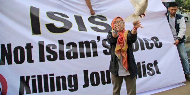 A Muslim woman releases a dove as a symbol of peace during a rally against the Islamic State group, in Jakarta, Indonesia, Friday, Sept. 5, 2014. The banner reads: