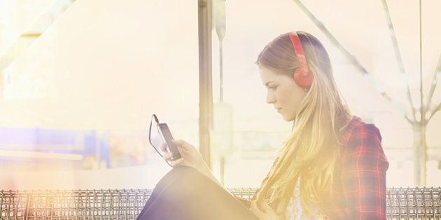 woman at station listening to music with mobile