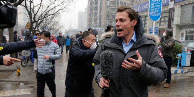 A foreign journalist covering rights lawyer Pu Zhiqiang's trial reacts after being pushed away by police offiers near the Beijing Second Intermediate People's Court in Beijing, Monday, Dec. 14, 2015. Pu went on trial Monday on charges of provoking trouble with commentaries on social media that were critical of the ruling Communist Party. (AP Photo/Andy Wong)