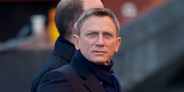 Actor Daniel Craig jokingly pulls a face at photographers as he films a scene with Rory Kinnear, back obscured, on a canal for the new James Bond movie,