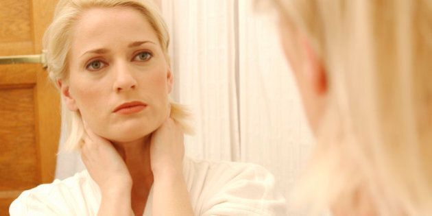Woman Looking At Her Face In Bathroom Mirror