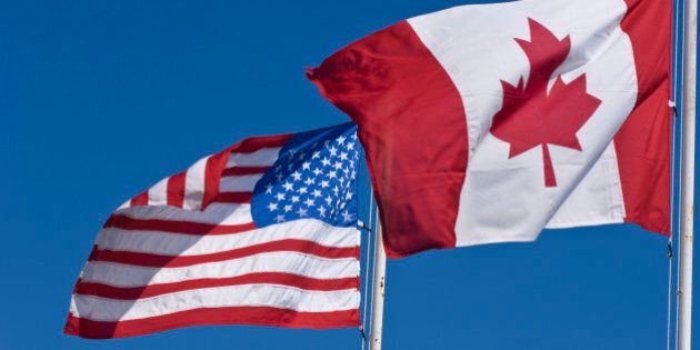 Canadian and United States flags on blue sky