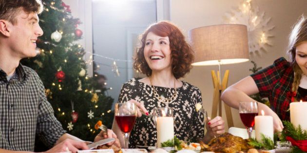 Friends laughing and eating Christmas dinner.