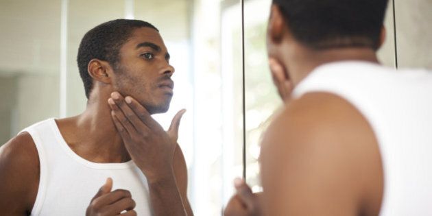 Shot of a handsome young man applying moisturizer to his face