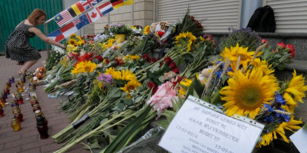 People lay flowers at the Netherlands Embassy for the Malaysia Airlines Flight MH17 crash victims, in Kiev, Ukraine, Friday, July 17, 2015. Residents of the Ukrainian village where the Malaysian airliner was shot down with 298 people aboard a year ago joined a procession to the crash site on Friday, while Australia's prime minister remembered the