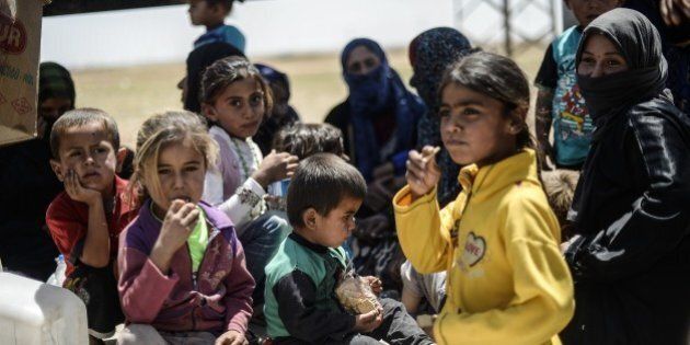 Syrian refugees sit on the side of a road that leads to the Akcakale border gate as they wait to return to their home in the northern Syrian town of Tel Abyad, in Sanliurfa province, on June 18, 2015. Almost 60 million people worldwide were forcibly uprooted by conflict and persecution at the end of last year, the highest ever recorded number, the U.N. refugee agency said. UNHCR said Syria, where conflict has raged since 2011, was the world's biggest source of internally displaced people and refugees. There were 7.6 million displaced people in Syria by the end of last year and almost 4 million Syrian refugees, mainly living in the neighbouring countries of Lebanon, Jordan and Turkey. AFP PHOTO/BULENT KILIC (Photo credit should read BULENT KILIC/AFP/Getty Images)