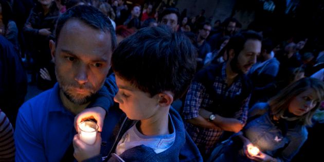FILE- In this Monday, Nov. 16, 2015, file photo, a man holds a child in his arms outside of the French embassy in Mexico City during a vigil for the victims of the terrorist attacks in Paris. After the France terror attacks, schools and parents around the world are grappling with what to say to children, and how to say it. From country to country, the topic was tackled in different ways. (AP Photo/Marco Ugarte, File)