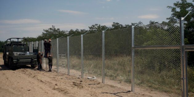 Hungarian soldiers build a fence near Morahalom, Hungary, Thursday, July 16, 2015. A fence on Hungary's border with Serbia to stem the flow of migrants and refugees will be complete by Nov. 30, the Hungarian defense minister said Thursday. Csaba Hende said that 900 people would work to install the fence, which is planned to be 4 meters (13 feet) high along the 175-kilometer (109-mile) border between Hungary and Serbia. (AP Photo/Darko Vojinovic)