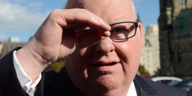 Sen. Mike Duffy shields his eyes as he arrives at the Senate on Parliament Hill in Ottawa on Tuesday, Oct. 22, 2013. THE CANADIAN PRESS/Sean Kilpatrick