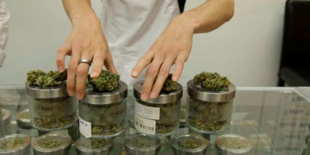 In this Friday, June 26, 2015 photo, an employee at the medical marijuana dispensary Kaya Shack displays different types of marijuana flowers sold at the shop in Portland, Ore. On July 1, recreational marijuana in Oregon is legal, but it's likely customers won't be able to buy the pot at medical dispensaries until October 1. (AP Photo/Gosia Wozniacka)