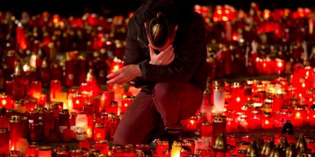 A man touches his forehead holding a candle outside the Colectiv nightclub in Bucharest, Romania, Friday, Nov. 6, 2015, as people mark one week since a deadly fire started during a concert. Romanian prosecutors on Friday questioned an owner of the nightclub where a fire killed 32 people and injured 180. (AP Photo/Vadim Ghirda)