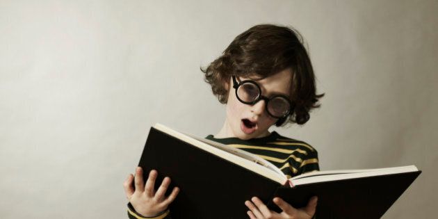 Boy (8-9) reading book, mouth open