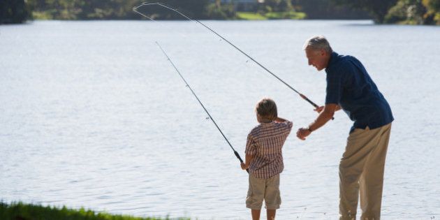 Man and young boy outdoors at park fishing in a lake