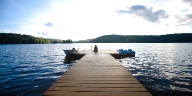 Person sitting on dock with two boats in water