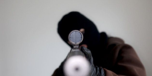 Man wearing a balaclava holding a sniper rifle.