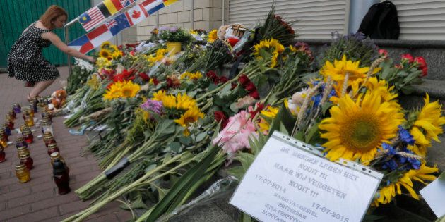 People lay flowers at the Netherlands Embassy for the Malaysia Airlines Flight MH17 crash victims, in Kiev, Ukraine, Friday, July 17, 2015. Residents of the Ukrainian village where the Malaysian airliner was shot down with 298 people aboard a year ago joined a procession to the crash site on Friday, while Australia's prime minister remembered the