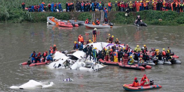 Emergency personnel try to extract passengers from a commercial plane after it crashed in Taipei, Taiwan, Wednesday, Feb. 4, 2015. The Taiwanese commercial flight with 58 people aboard clipped a bridge shortly after takeoff and crashed into a river in the island's capita on Wednesday morning. (AP Photo/Wally Santana)