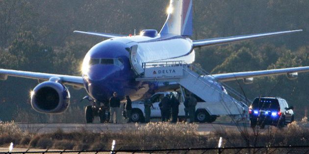Law enforcement officials stand beneath a Southwest Airlines airplane on the tarmac at Hartsfield-Jackson Atlanta International Airport, Saturday, Jan. 24, 2015, in Atlanta. Police were searching two planes at Atlanta's main airport after authorities received what they described as