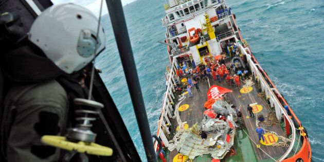 In this photo taken from an Indonesian Air Force Super Puma helicopter Saturday, Jan. 10, 2015, portion of the tail of AirAsia Flight 8501 is seen on the deck of a rescue ship after it was recovered from the sea floor on the Java Sea. Investigators searching for the crashed AirAsia plane's black boxes lifted the tail portion of the jet out of the Java Sea on Saturday, two weeks after it went down, killing all 162 people on board. (AP Photo/Prasetyo Utomo, Pool)