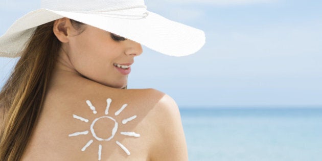 Young Woman Looking At Sun Drawn On Her Back With Suntan Lotion