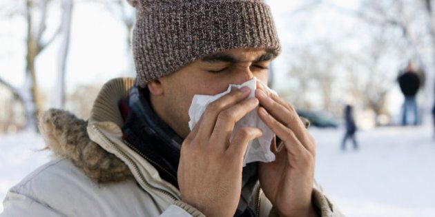Mixed race man blowing nose outdoors