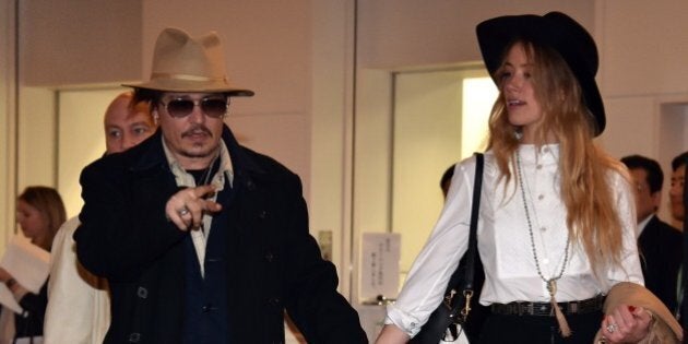 US actor Johnny Depp (L), accompanied by his fiancee US actress and model Amber Heard (R), arrive at Tokyo International Airport on January 26, 2015 for the Japan premiere of his latest movie 'Mortdecai'. The action comedy movie will be screened in Japan from February 6. AFP PHOTO (Photo credit should read YOSHIKAZU TSUNO/AFP/Getty Images)